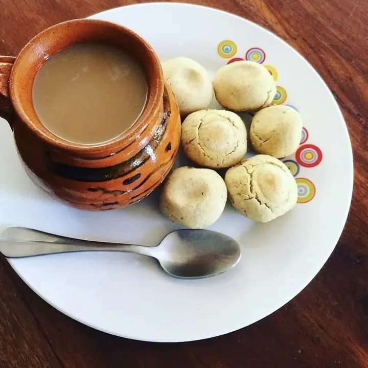 Round Salvadoran totopostes on a plate next to a cup of coffee