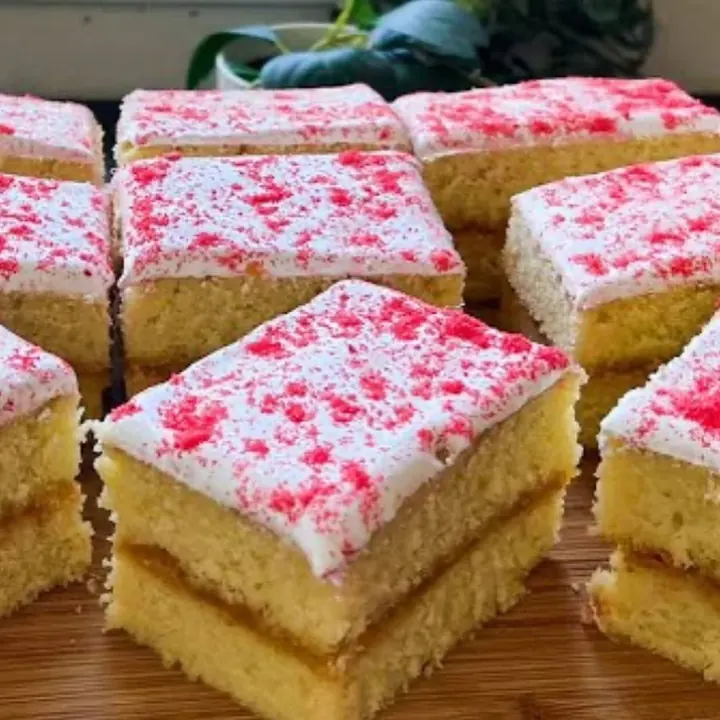 Squares of María Luisa cake with jam and pink sugar on top