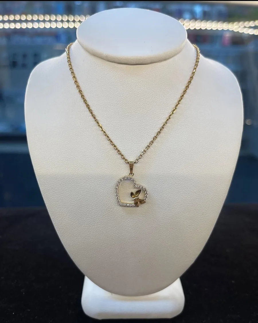 Gold necklace with an open heart and butterfly pendant on a display bust