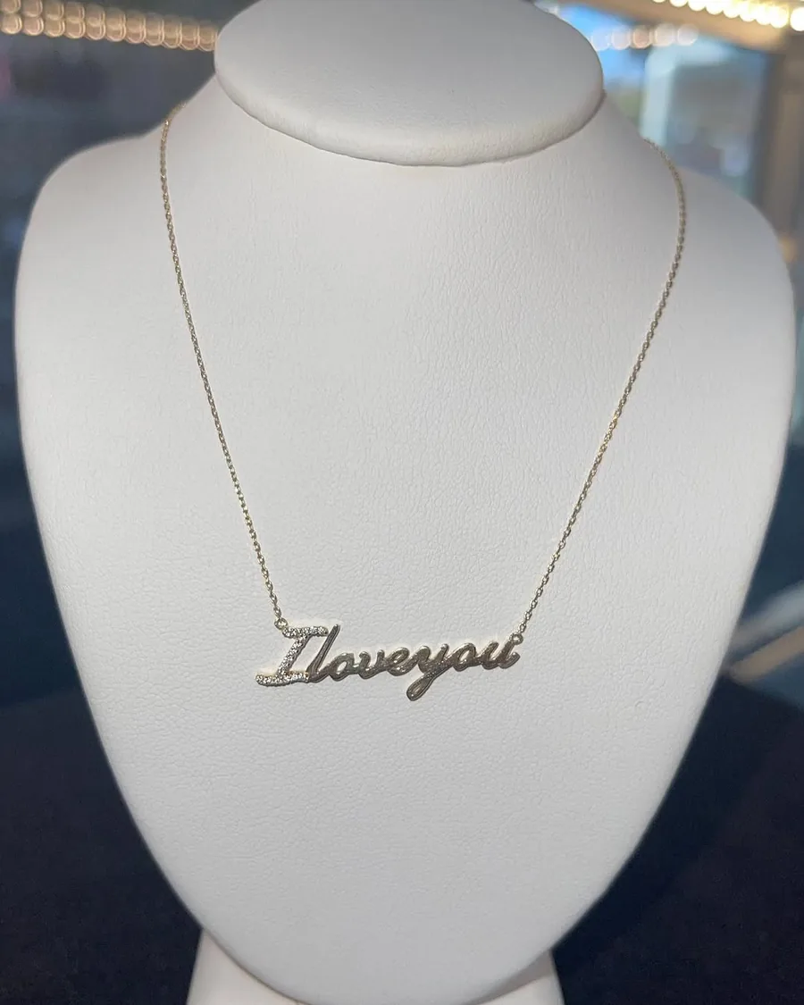 Gold “I love you” script necklace on a display bust