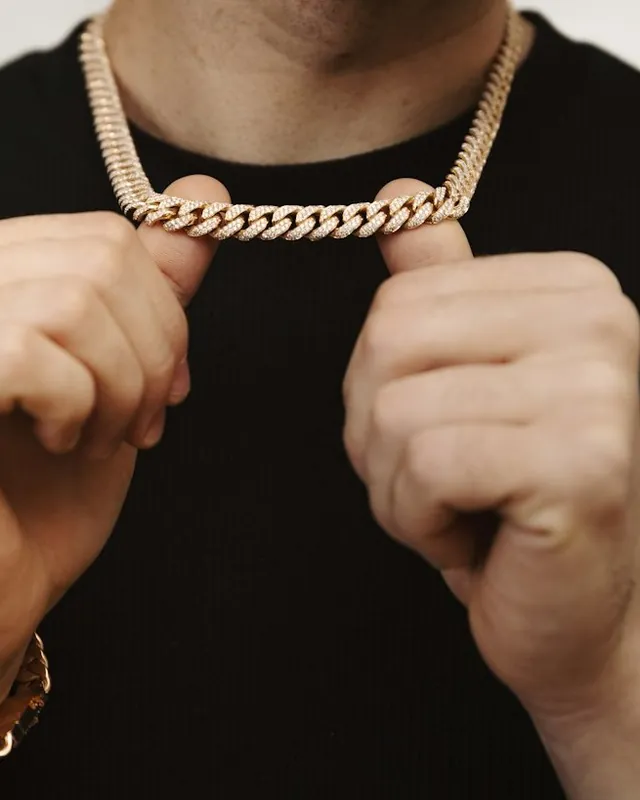 Man holding a gold Miami Cuban link chain at his neck